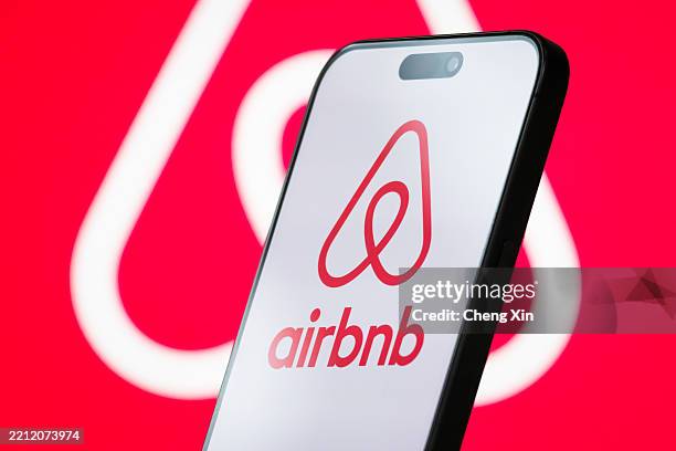 In this photo illustration, the logo of Airbnb, Inc. Is displayed on a smartphone screen, with the company's branding visible in the background, on...