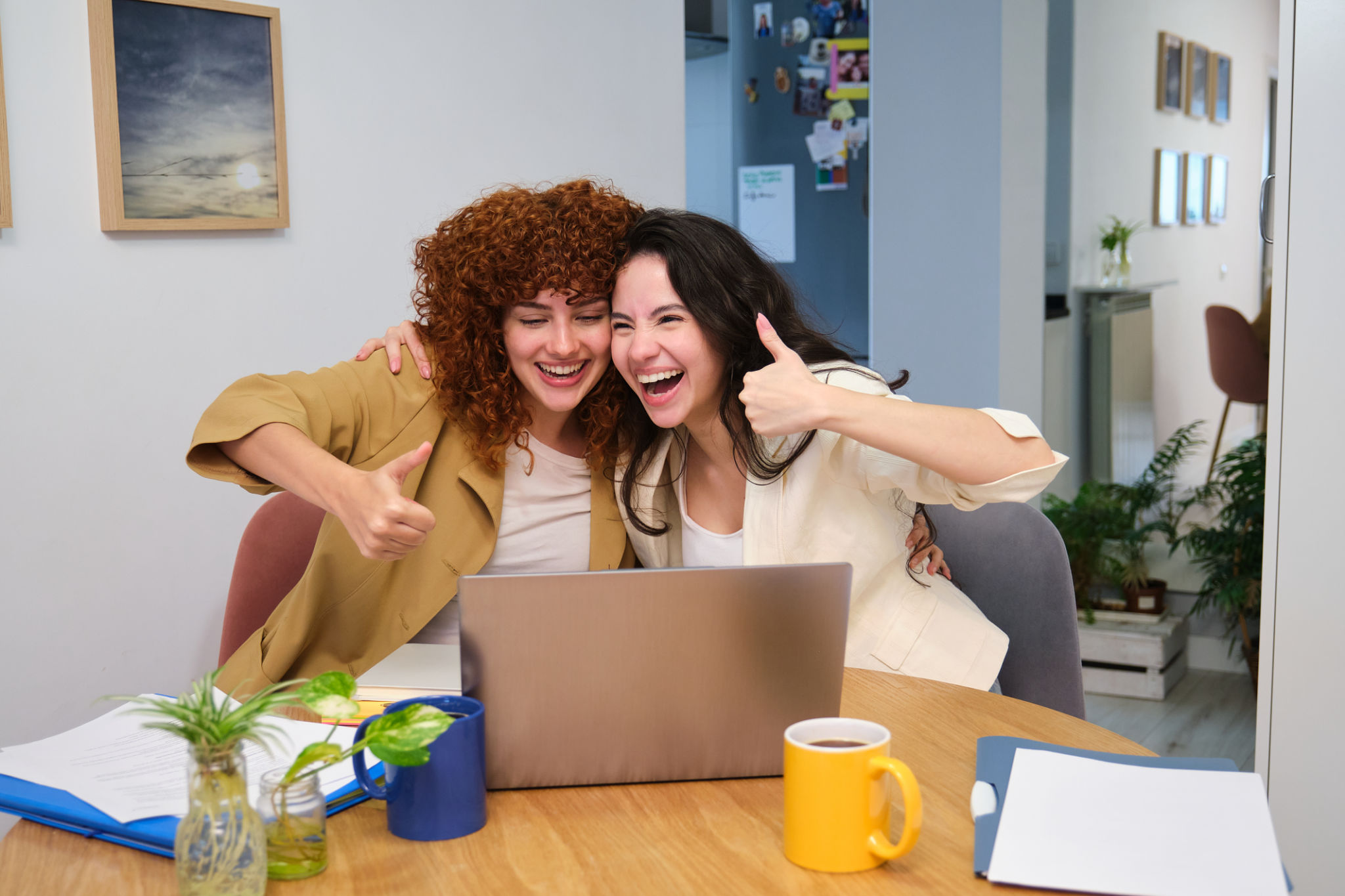 Two happy female entrepreneurs showing thumbs up while working from home Two happy female entrepreneurs showing thumbs up while working from home
