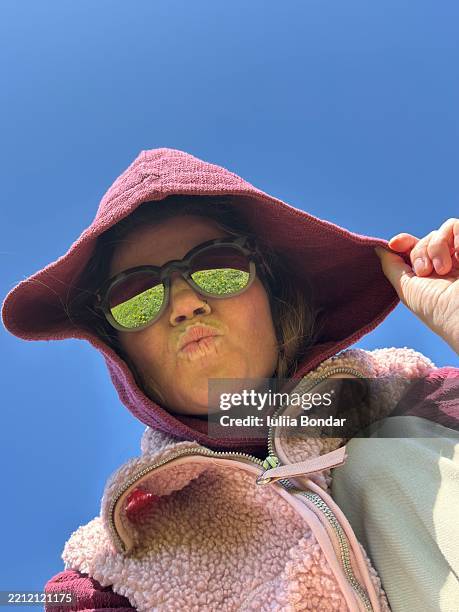 cheerful girl in hoodie laughing outdoors with sunny blue sky - send kiss stock pictures, royalty-free photos & images