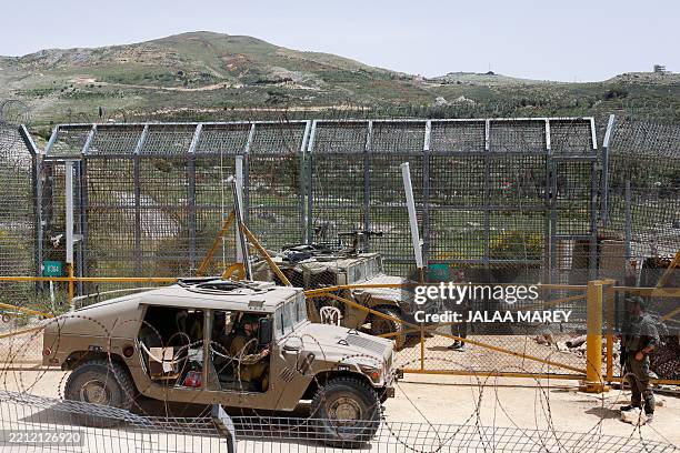 Israeli soldiers stand guard as Druze men demonstrate in solidarity with the Syrian Druze community near the border barrier in the village of Majdal...