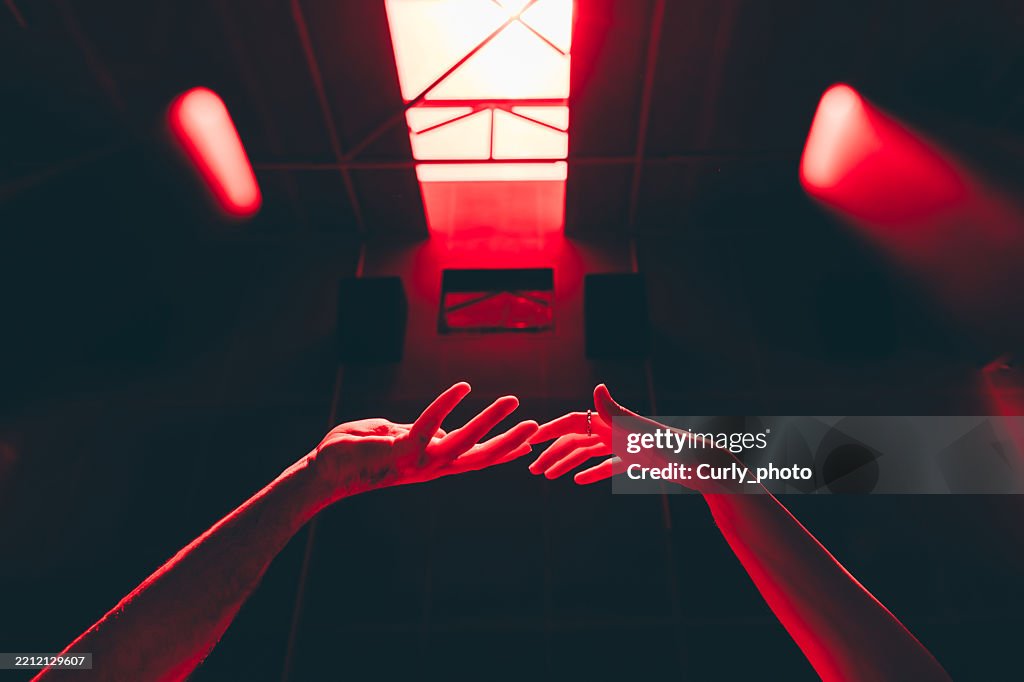 Hands of a couple touching in red light. A romantic, emotional moment, searching for a soul mate.