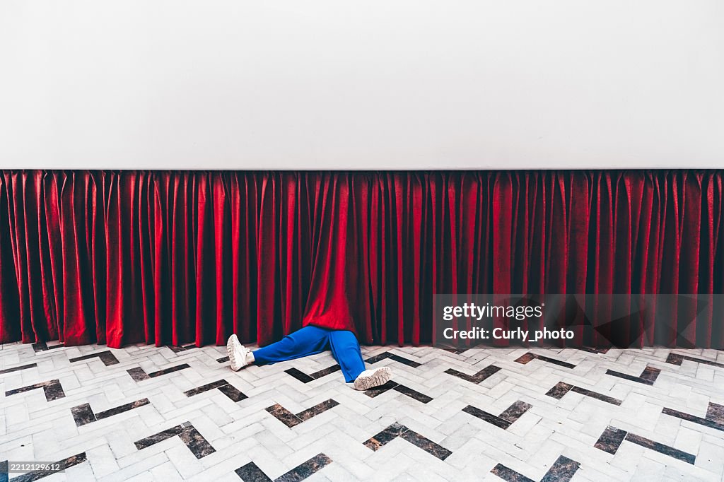 Legs of a woman sticking out from red curtain.