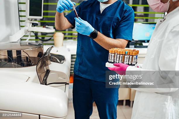 medical laboratory technicians analyzing blood sample in a centrifuge machine - hematology stock pictures, royalty-free photos & images