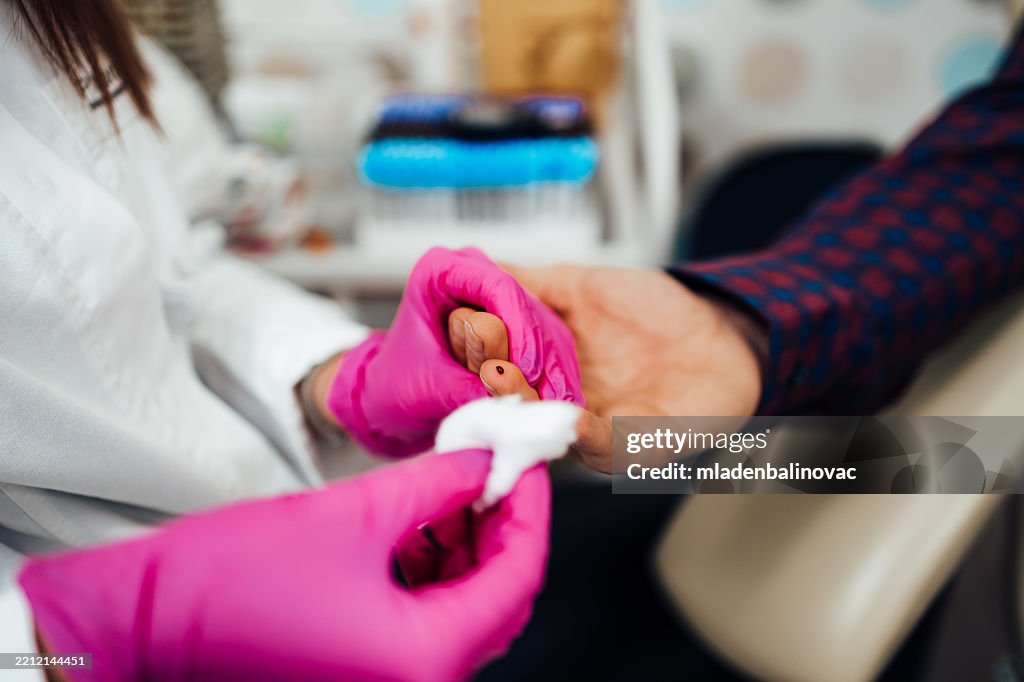 Doctor taking blood sample from patient's finger for medical test
