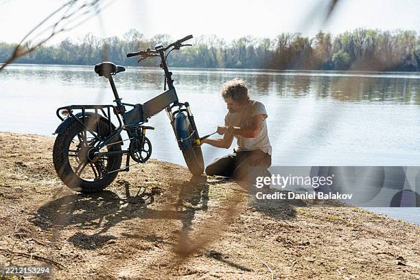 fahrradreisender pumpt reifen auf seinem e-bike in der natur - luftpumpe stock-fotos und bilder