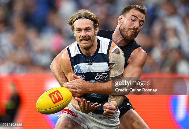 Tom Stewart of the Cats handballs whilst being tackled by Harry McKay of the Blues during the round seven AFL match between Carlton Blues and Geelong...