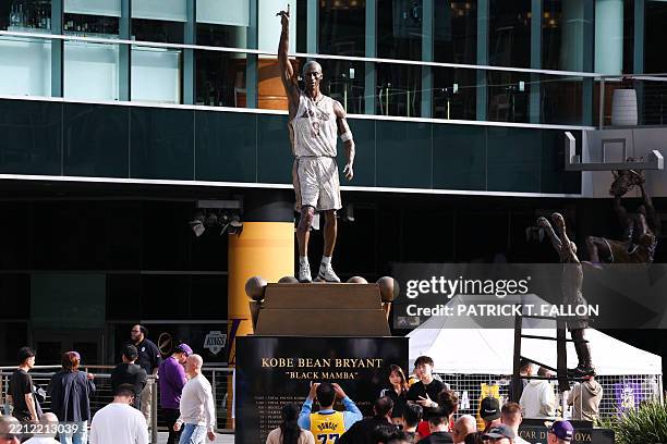 Person wears the number jersey of Slovenian basketball player Luka Doncic while taking a photo of the memorial statue for late Lakers player Kobe...