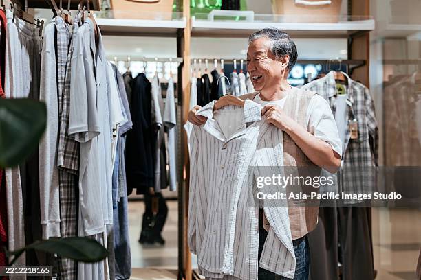 homme senior asiatique achetant des vêtements décontractés en magasin. - industrie de la mode photos et images de collection