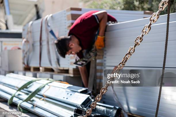 worker handling metal panels during industrial loading operation - structural steel stock pictures, royalty-free photos & images
