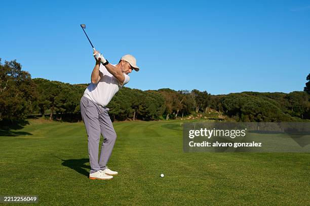 golfer concentrating on perfecting swing on sunny golf course - golf club stock pictures, royalty-free photos & images