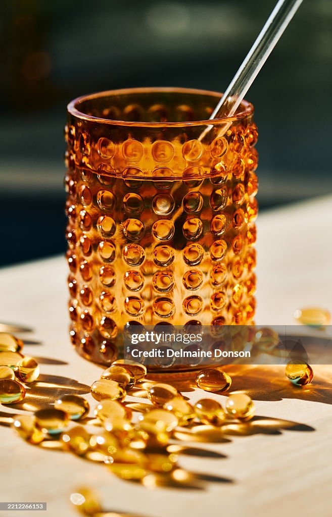 Golden Capsules with Amber Glass in Sunlight