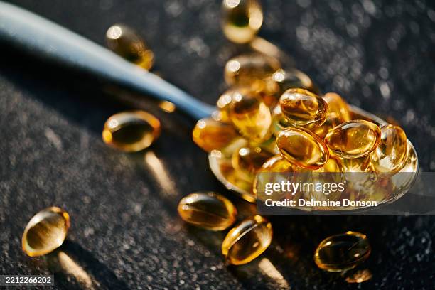 golden softgel capsules on silver spoon - gold capsules stock pictures, royalty-free photos & images