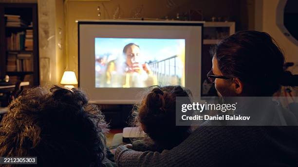 smart home cinema. happy family watching movie at home - projectie stockfoto's en -beelden