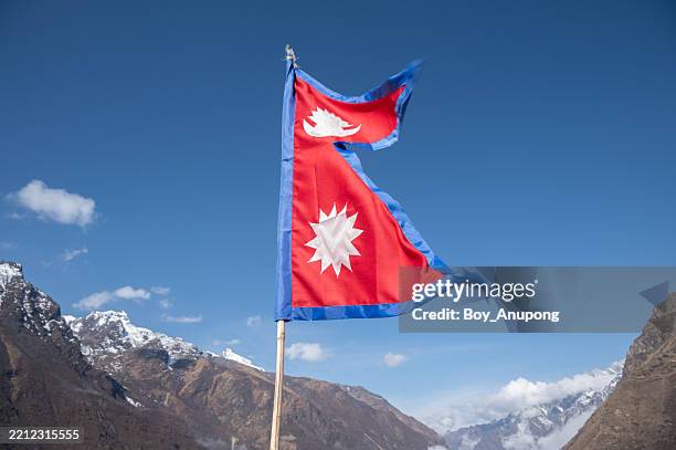 nepali flag blowing by the wind against the blue sky in langtang national park, nepal. - nepal flag stock pictures, royalty-free photos & images