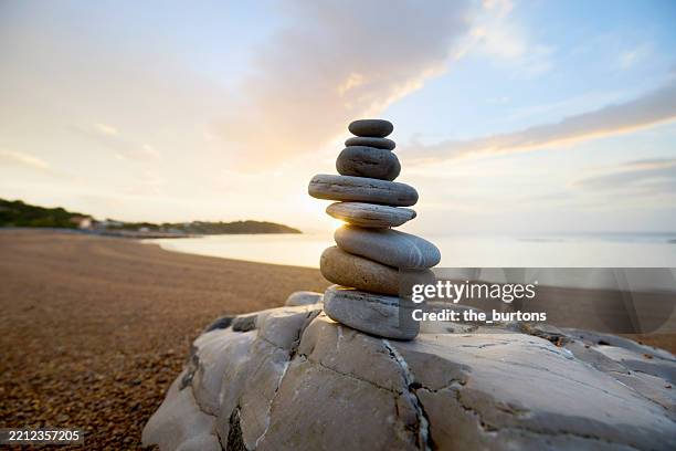 stack of balanced stones at beach at idyllic sunset - pile of rocks stock pictures, royalty-free photos & images