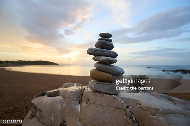 stack of balanced stones at beach at idyllic sunset - estabilidade imagens e fotografias de stock
