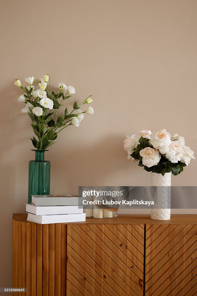 Wooden Sideboard with Tulips and Candles on White Wall Background