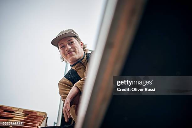 portrait of a confident carpenter on the roof of a house - dakdekker stockfoto's en -beelden