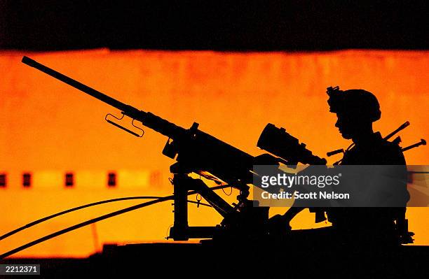 Soldier with the U.S. Army 101st Airborne 3-502 is silhouetted manning a 50 caliber humvee-mounted machine gun as his squad heads out on a nighttime...