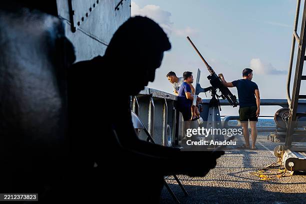 Philippine Naval soldier texts his family on a limited satellite network using his phone while the others chat on the weather deck of the warship, in...
