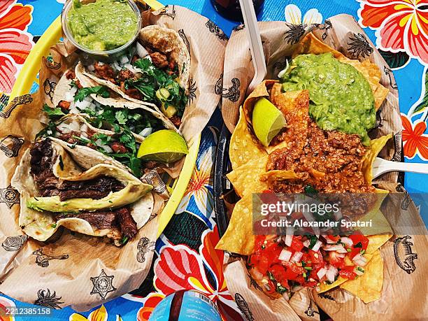 various tacos and nachos with guacamole and chili con carne served at a street food festival - mexican food stock pictures, royalty-free photos & images