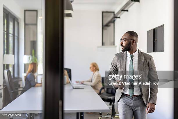 businessman walking confidently through a collaborative space - formal businesswear stock pictures, royalty-free photos & images