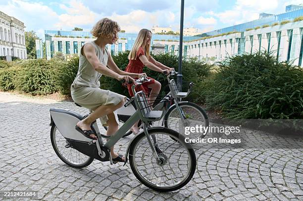 two women riding bicycle in an urban park - warsaw stock pictures, royalty-free photos & images