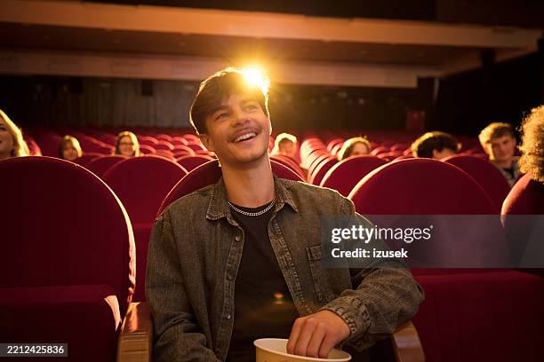 joy in the cinema: young man laughing in the theater - watching stock pictures, royalty-free photos & images