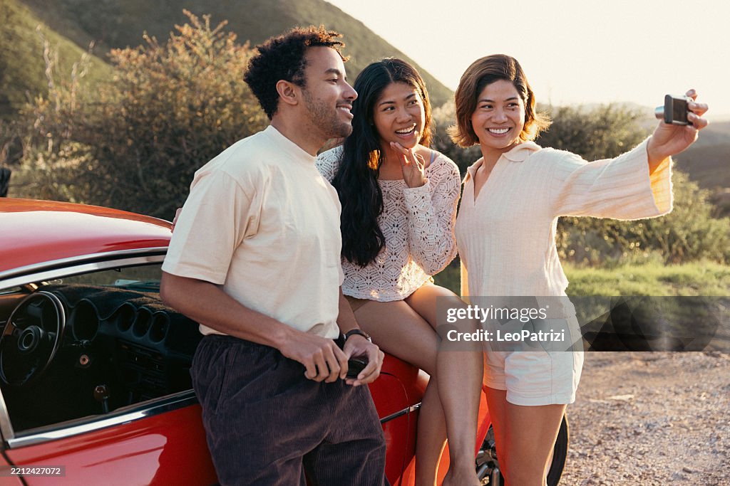 Amigos con un coche de época con una cámara compacta digital de principios de la década de 2000