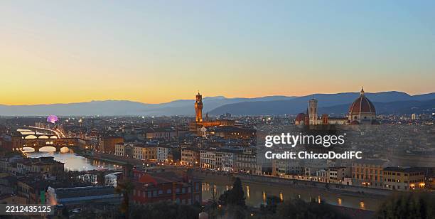 panoramic view of the city of Florence at night with the city lights on with the profile of the Tuscan mountains and hills in the distance