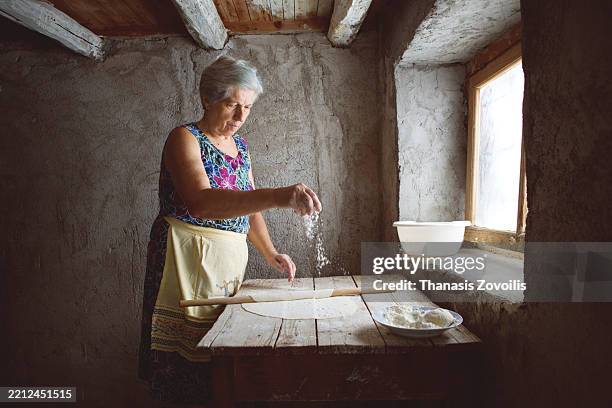 woman preparing dough in rustic kitchen during daylight hours - greek food stock pictures, royalty-free photos & images
