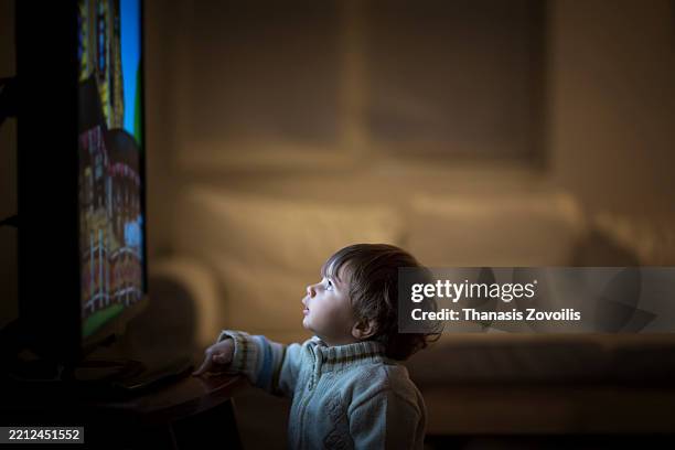 child fascinated by colorful animation on television during evening - finding time stock pictures, royalty-free photos & images