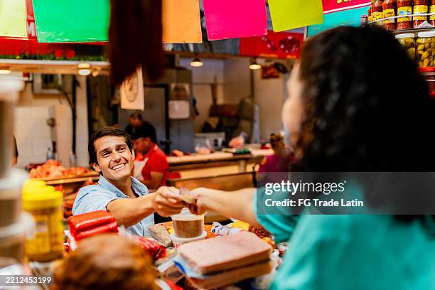 mid adult man buying a snack to seller at store - nafta stock pictures, royalty-free photos & images
