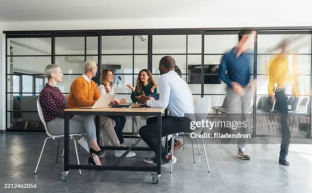 dynamics of collaboration: engaged discussions in a modern office - staff meeting stock pictures, royalty-free photos & images