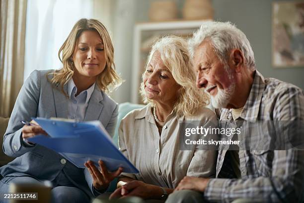 female agent and her mature customers reading plans at home. - erfenis stockfoto's en -beelden