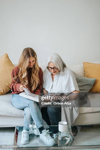 mother and daughter looking at a family photo album - photo album stock pictures, royalty-free photos & images