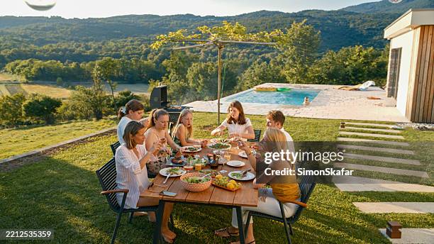 family enjoying a meal together outdoors in their backyard - comfort food stockfoto's en -beelden