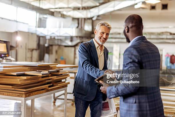 professionals shaking hands in a modern industrial workshop setting - suit making stock pictures, royalty-free photos & images