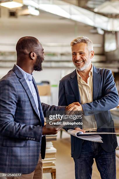 two business professionals shaking hands in a friendly office setting - happy colleagues doing team building activity imagens e fotografias de stock