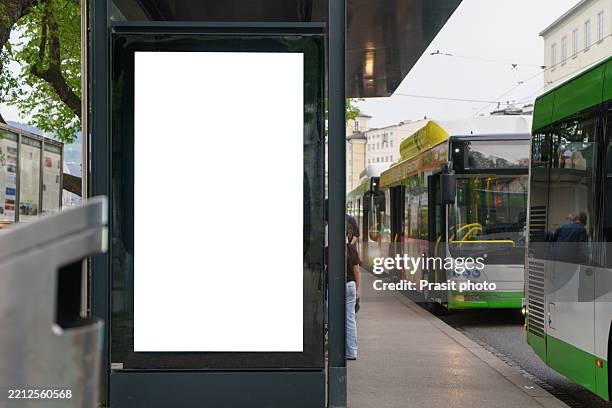 blank bus-shelter lightbox at city transit stop with modern trolleybuses - bushaltestelle stock-fotos und bilder