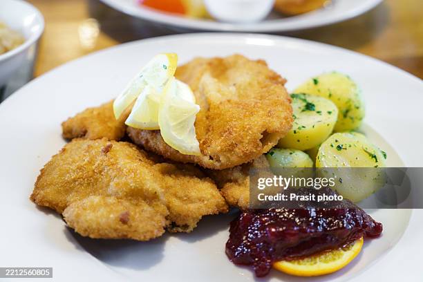 traditional wiener schnitzel with parsley potatoes and cranberry sauce - austrian culture stock pictures, royalty-free photos & images