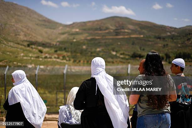 Druze families wave to relatives fleeing sectarian violence in Damascus, as they arrive in the buffer zone across from the village of Majdal Shams in...