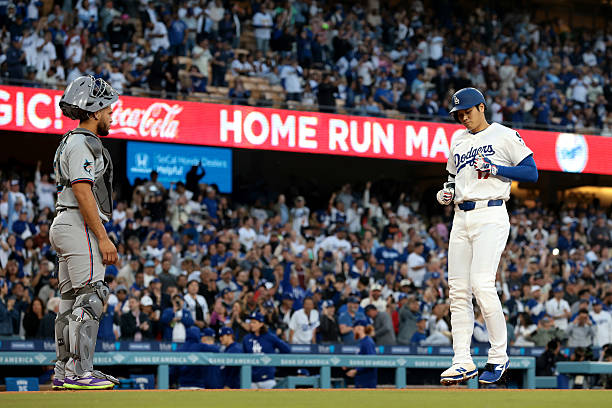 Shohei Ohtani of the Los Angeles Dodgers crosses home plate after hitting a home run as Agustín Ramírez of the Miami Marlins looks on during the...