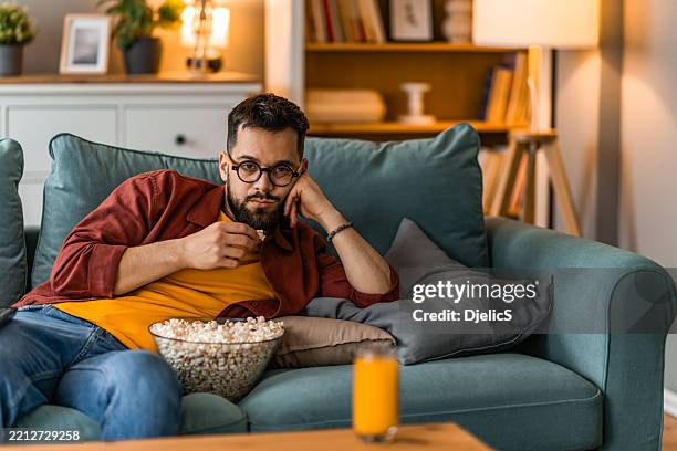 bored man watching a movie on tv at home. - bed rotting stock pictures, royalty-free photos & images