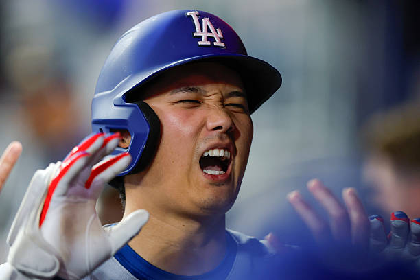 Shohei Ohtani of the Los Angeles Dodgers reacts in the dugout after hitting a solo home run during the third inning against the Atlanta Braves at...