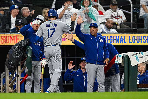 Los Angeles designated hitter Shohei Ohtani gets a high-five from manager Dave Roberts after scoring a run during the MLB game between the Los...