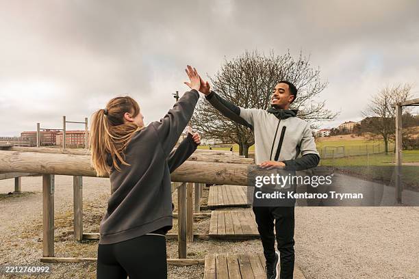 two friends in workout clothes giving a high five at an outdoor gym. - gym 81 stock pictures, royalty-free photos & images