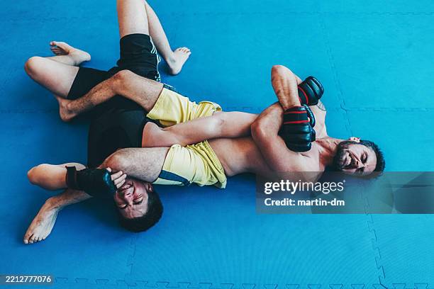 mixed martial arts fighters practicing grappling techniques on mat - mixed martial arts stock pictures, royalty-free photos & images