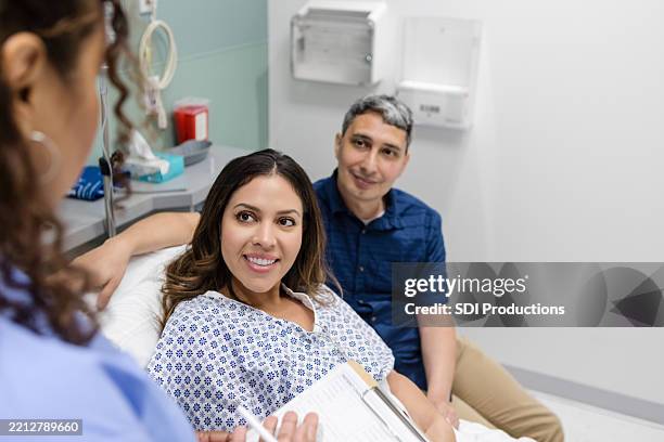 couple heureux au cabinet du médecin, discutant des soins de santé - contact avec les patients photos et images de collection