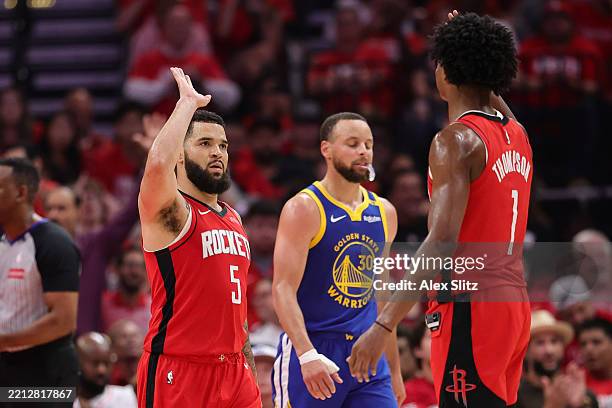 Fred VanVleet and Amen Thompson of the Houston Rockets high five in front of Stephen Curry of the Golden State Warriors during the third quarter in...